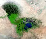 Satellite mosaic of a shallow lake largely covered by dense green marsh vegetation, with blue open water and dark vegetated islands.