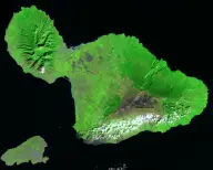 Satellite view of a green double-lobed volcanic island formed by two mountain masses joined by a narrow central plain, with a smaller island nearby.